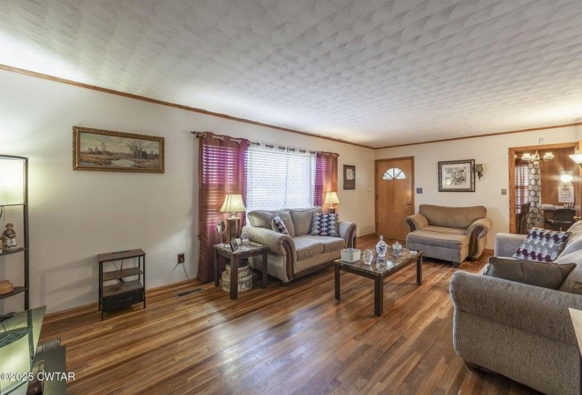 Spacious living area featuring wood-finish flooring, white walls, and wood trim