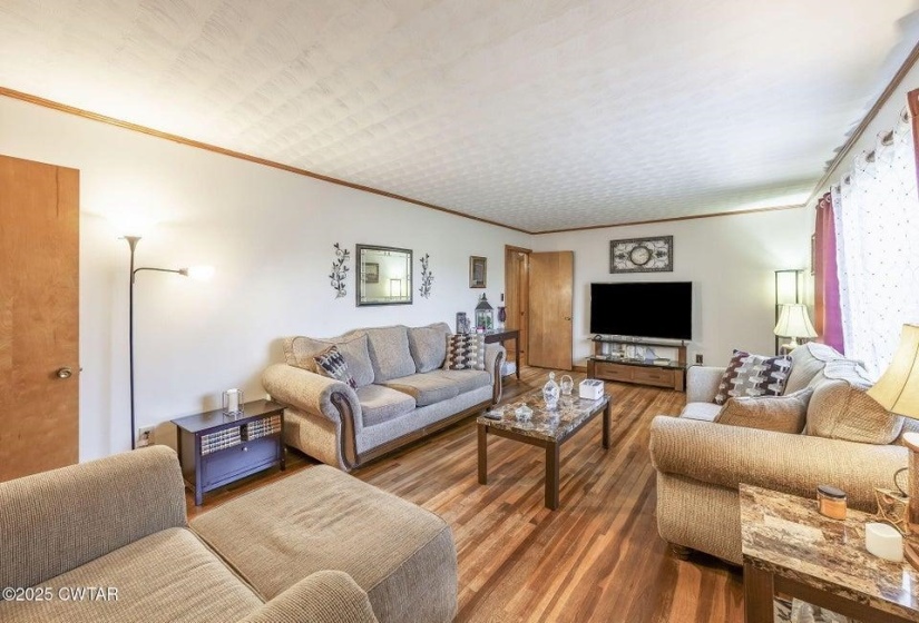 Spacious interior room featuring wood-finish flooring, white walls, and wood trim