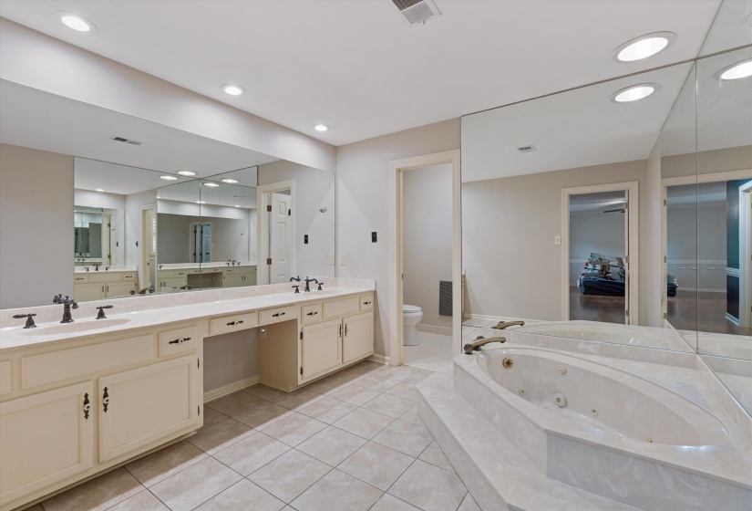 Private luxury bath featuring double vanity, sunken jetted tub, walk-in shower, water closet, and tile flooring.