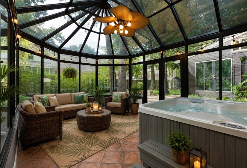 Vaulted Solarium with ceramic tile flooring, hot tub, double-pane windows, and access to Patio with stone firepit and benches. Virtually Staged Photo
