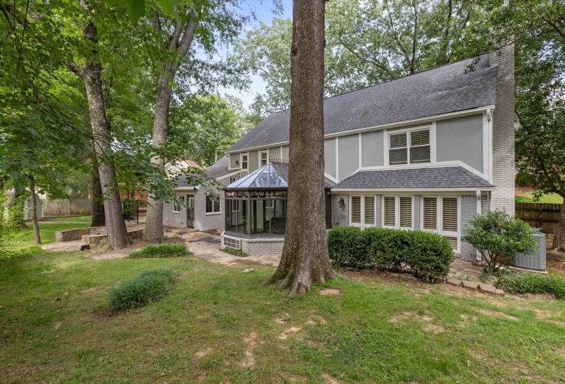 Private, tree-shaded backyard with beautiful rear elevation featuring an impressive glass Solarium, extensive stone patio areas, mature landscaping, and plenty of space for relaxing or entertaining. Scenic setting with multiple outdoor living areas.