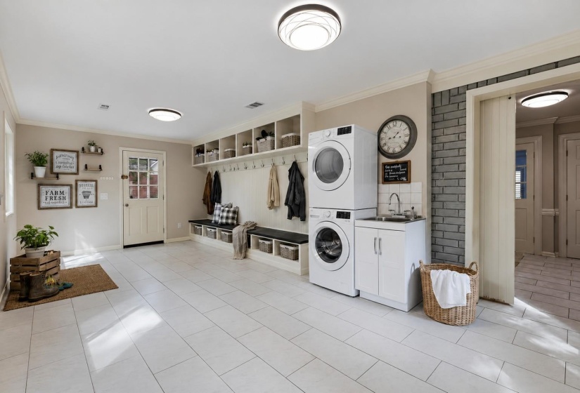 Oversized 23x12 Laundry Room with tile flooring, utility sink, and built-in kids’ cubby area for added convenience and organization - also adjacent to the separate Utility Room! Virtually staged photo.