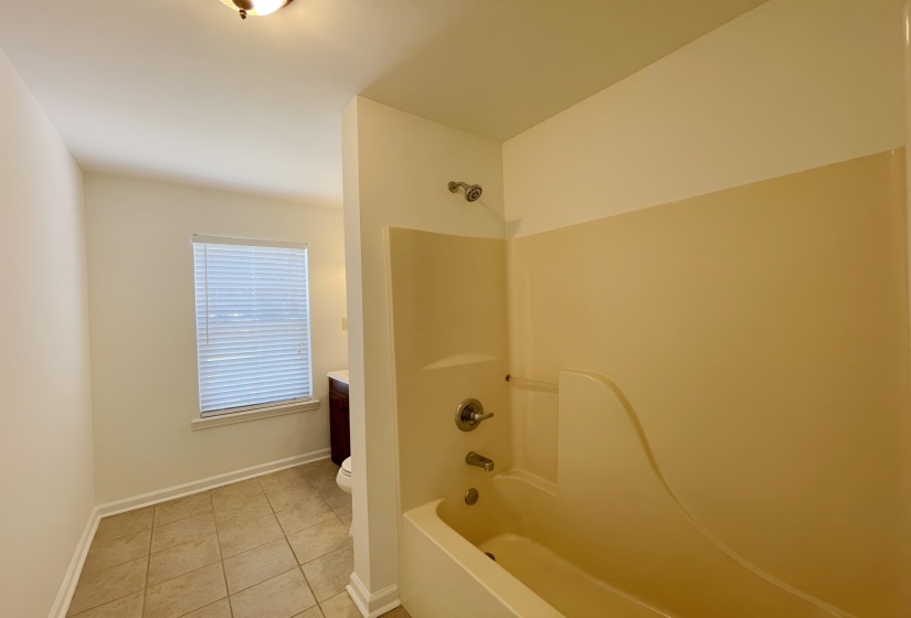Bathroom featuring a tub/shower combination with a single-handle faucet, tiled flooring, a window with blinds, and a built-in vanity with a sink and dark wood-finish cabinetry
