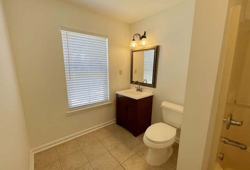 Bathroom featuring a dark wood-finish vanity with an integrated sink, brushed nickel faucet, and a decorative framed mirror