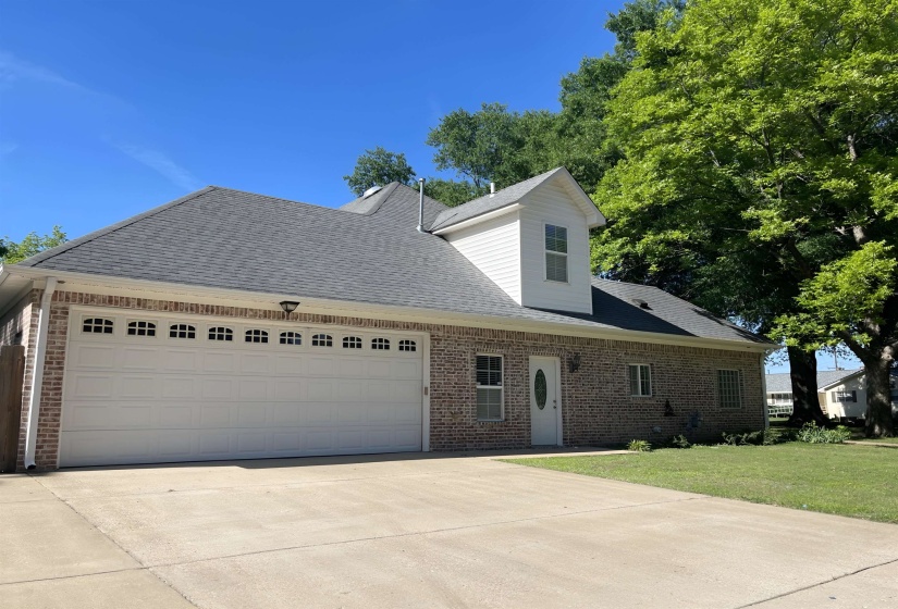 Brick exterior with white trim, featuring an attached two-car garage with decorative window inserts