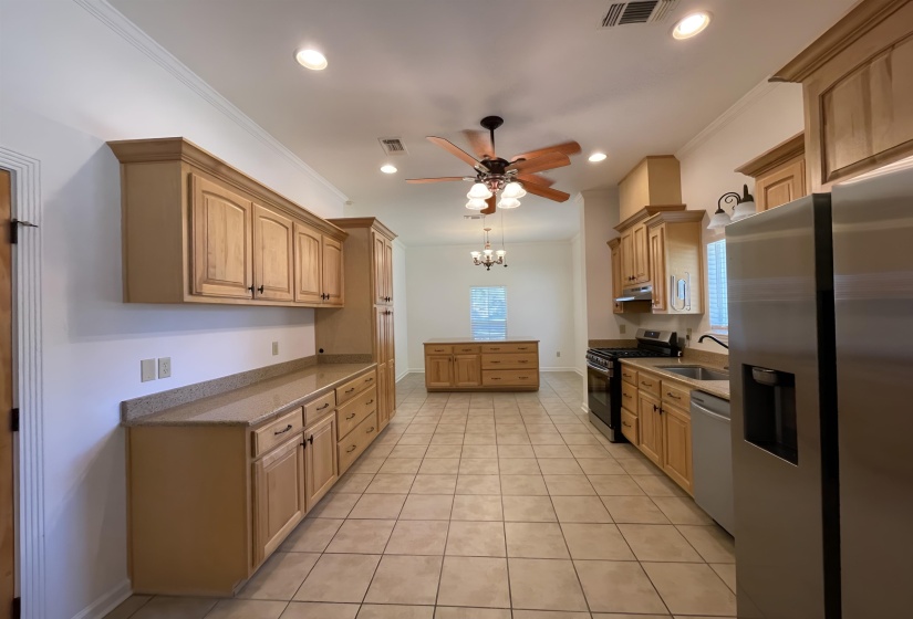 Kitchen featuring extensive wood cabinetry, stone-finish countertops, stainless steel appliances, and tiled flooring