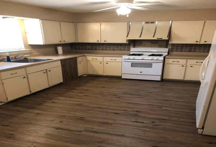 Kitchen featuring wood-finish flooring, a white gas range, and a tile backsplash