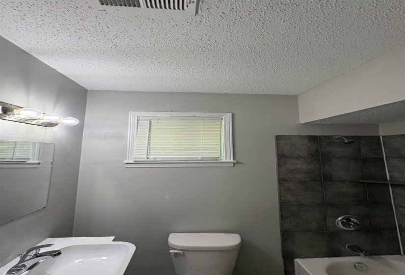 Bathroom featuring a white toilet, white vanity with a single basin sink, and a framed mirror