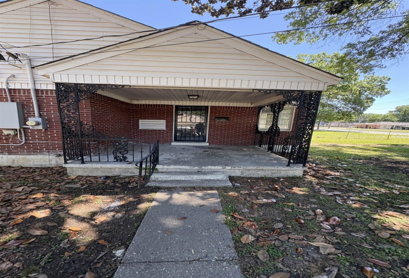 Brick exterior featuring a covered porch with decorative wrought iron railings