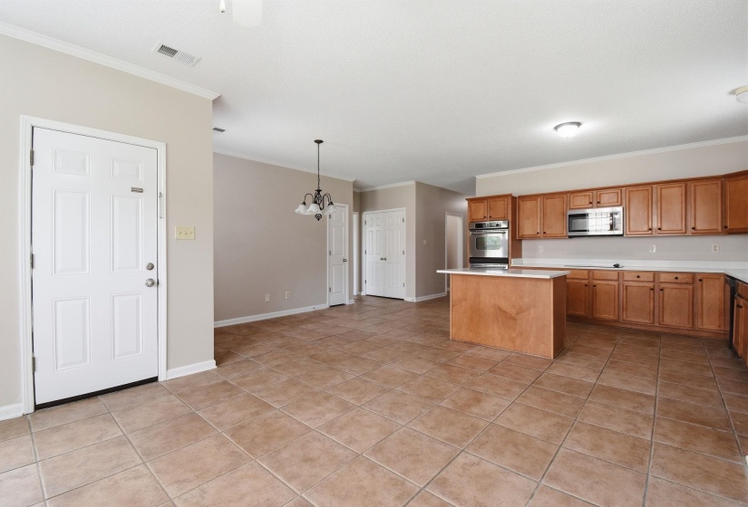 Spacious kitchen featuring wood cabinetry, stainless steel appliances, and a central island with white countertop