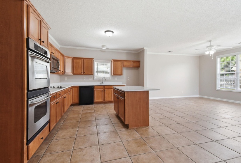 Kitchen featuring wood cabinetry, stainless steel double wall ovens, a built-in microwave, and a center island with countertop seating
