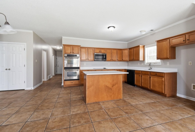 Kitchen featuring wood-finish cabinetry, white countertops, a central island, and stainless steel double wall ovens