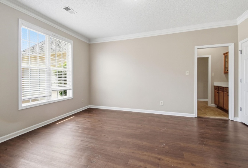 Expansive room featuring wood-finish flooring, neutral wall tones, and white crown molding