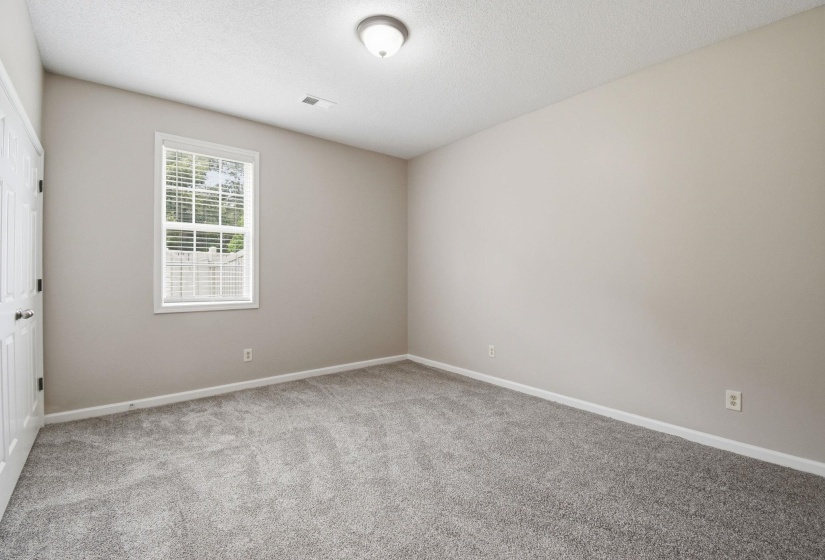Spacious room featuring neutral carpeting, light-toned wall paint, and white trim