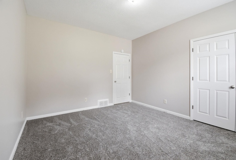 Room featuring light gray walls, gray patterned carpeting, white baseboards, and two white paneled doors