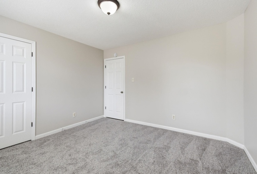 Bedroom featuring light gray wall paint, gray carpeting, white trim, and a white six-panel door