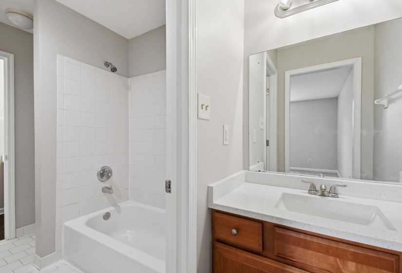 Bathroom featuring a light wood-finish vanity with a white composite countertop, an integrated sink, and chrome fixtures
