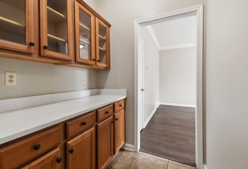 Built-in cabinetry with glass-front upper doors, white countertops, and wood-finish lower doors