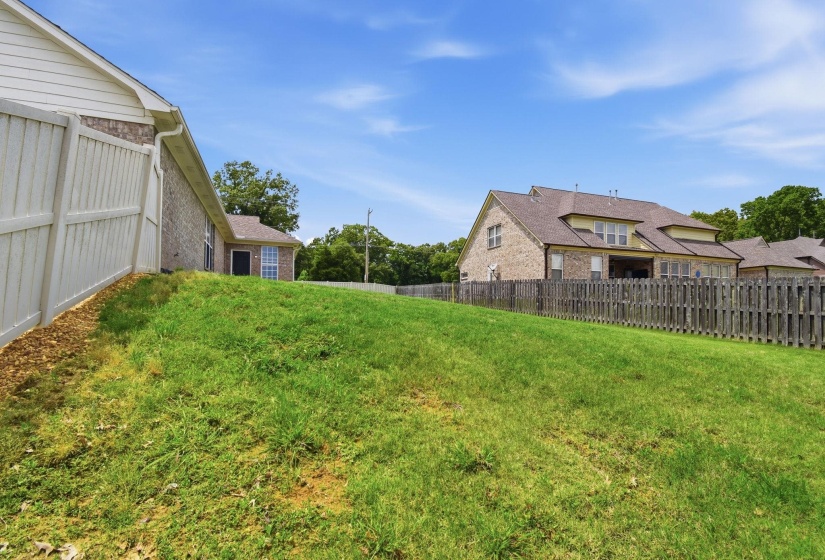 Expansive lawn area with a white privacy fence and a dark wood privacy fence