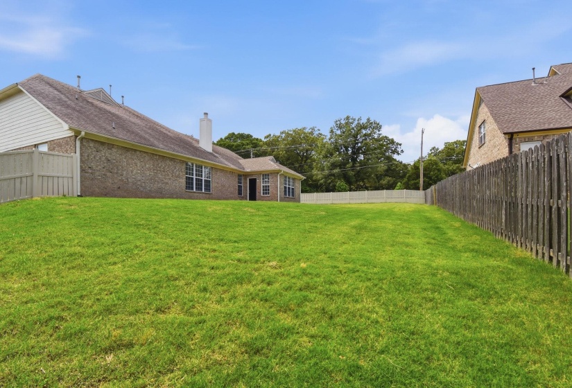 Expansive green lawn bordering a brick exterior residence with multiple windows and a white chimney