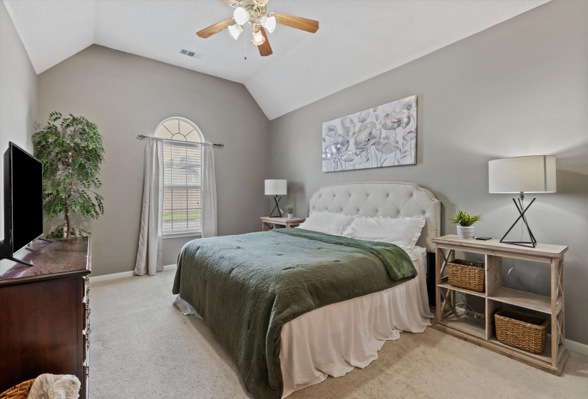 Wow! This spacious Vaulted ceiling primary is sure to impress! carpet, ceiling fan, arched window