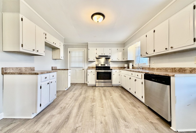 Kitchen with stainless steel appliances, crown molding, light wood finished floors, and white cabinets