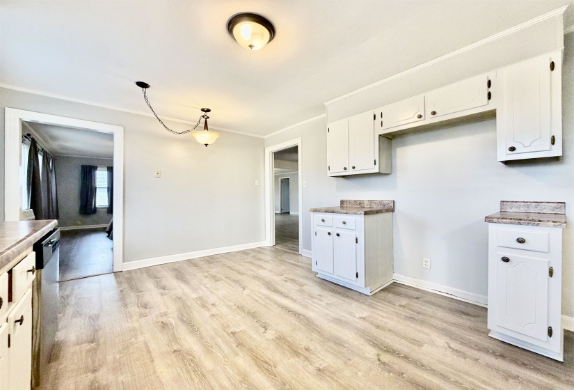 Kitchen featuring ornamental molding, white cabinets, light wood-style floors, dishwasher, and hanging light fixtures