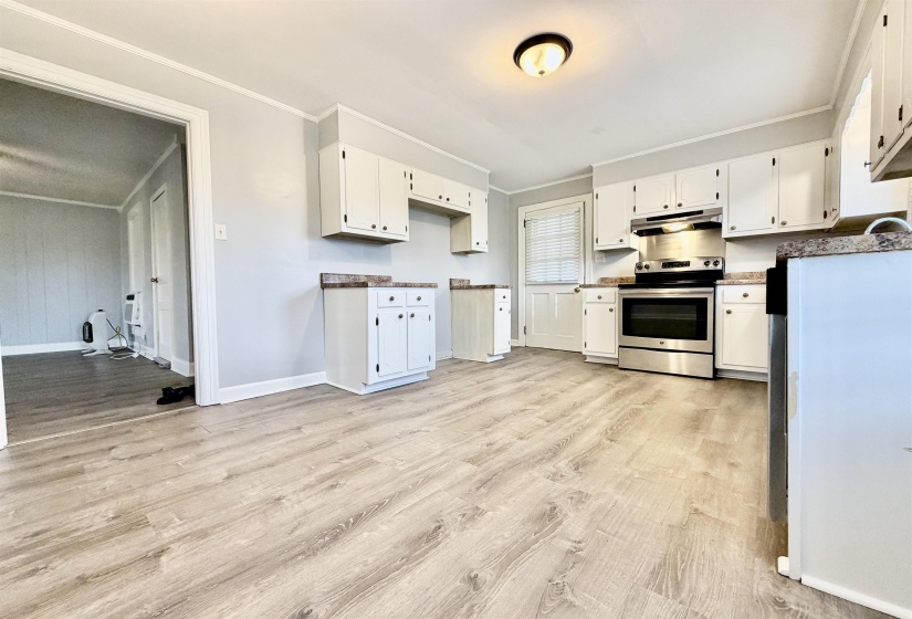 Kitchen with ornamental molding, stainless steel electric range, white cabinetry, and light wood-type flooring