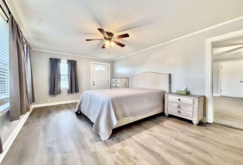 Bedroom with light wood-style floors, ornamental molding, ceiling fan, and a textured ceiling