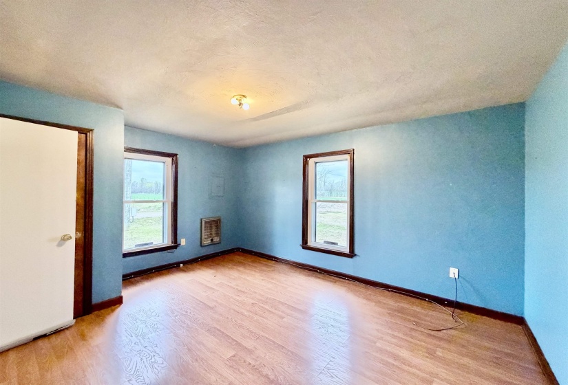 Empty room with light wood-style floors, a textured ceiling, and heating unit