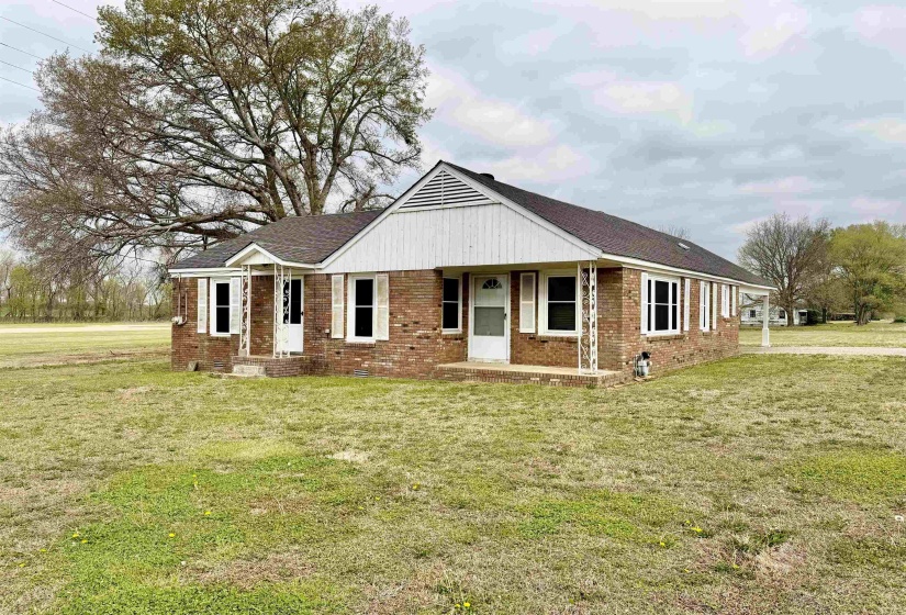 View of front of home featuring brick siding, a front lawn, and covered porch