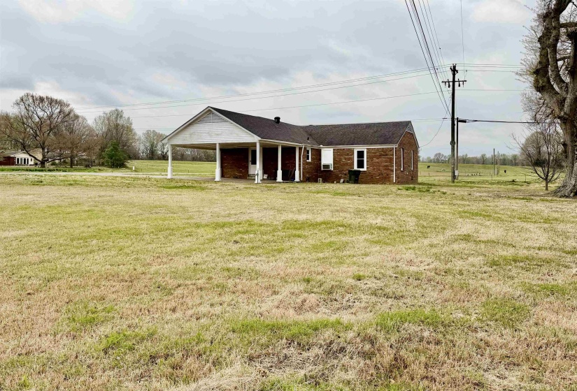 View of front of house featuring a carport, a front lawn, brick siding, and covered porch