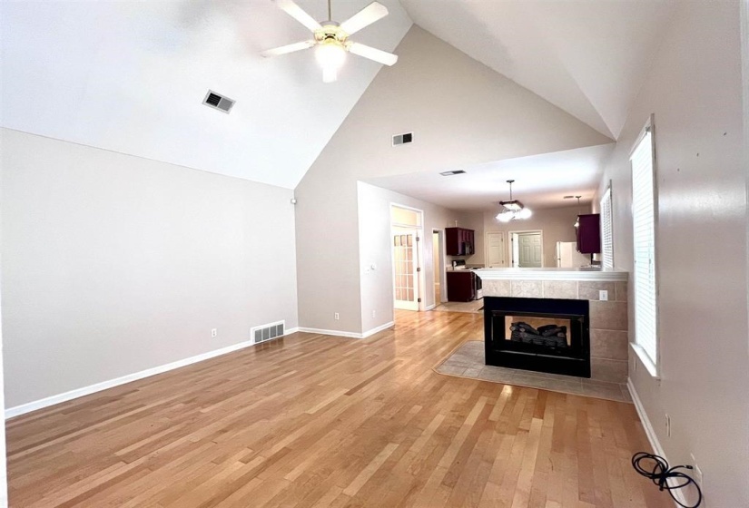 Unfurnished living room with a ceiling fan, a high ceiling, light wood-type flooring, and a fireplace