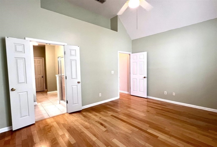 Unfurnished bedroom with light wood-style floors, lofted ceiling, and ceiling fan