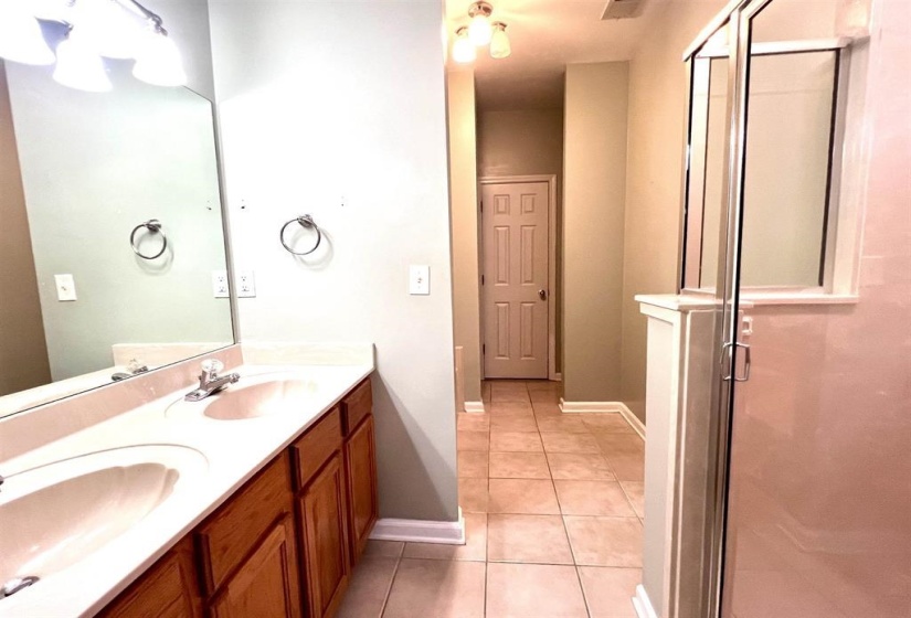 Bathroom featuring double vanity, a shower stall, and light tile patterned floors
