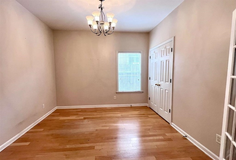 Empty room featuring light wood-style flooring and hanging lights