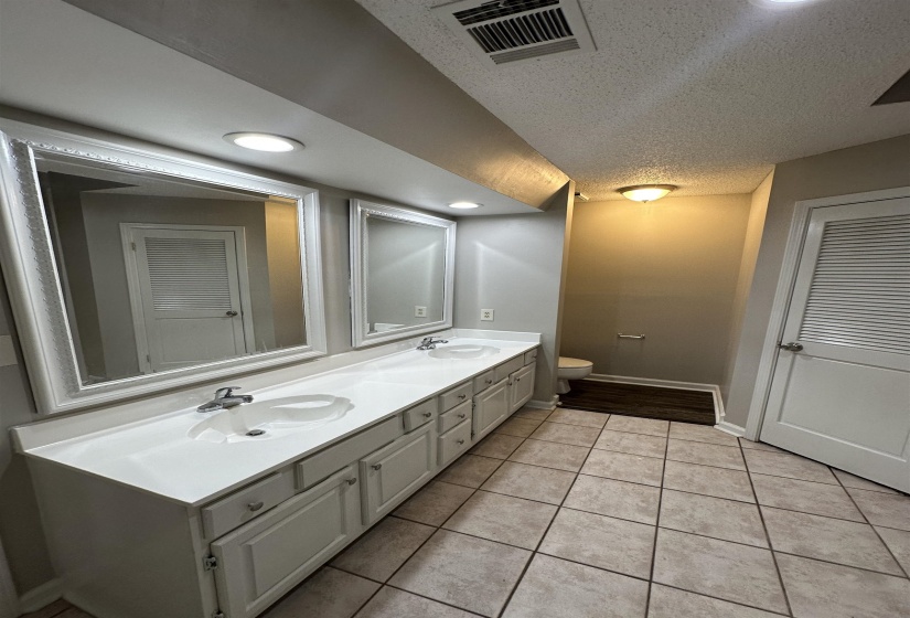 Double vanity featuring two integrated sinks, ample counter space, and white cabinetry with silver-tone hardware