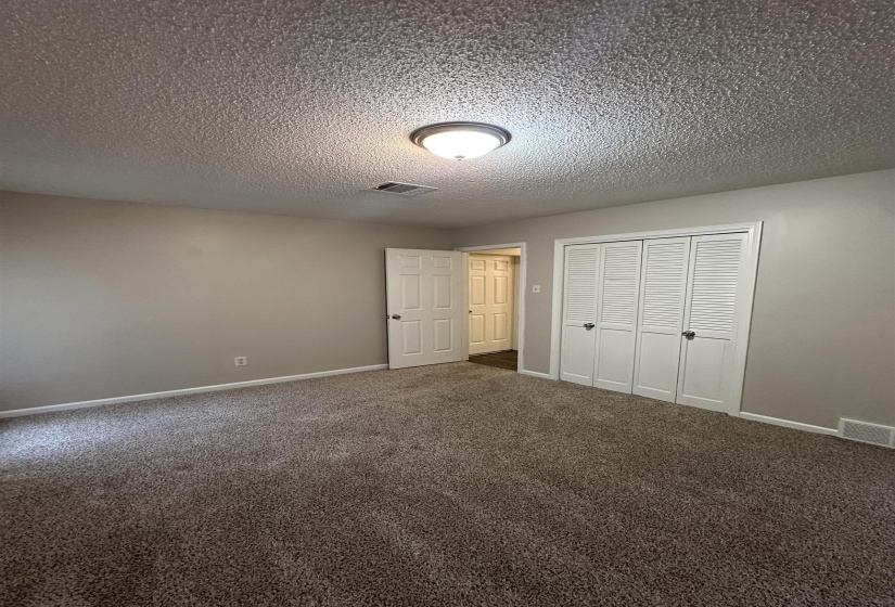 Carpeted room featuring a ceiling-mounted light fixture, neutral wall paint, white trim, and a bi-fold closet with louvered doors