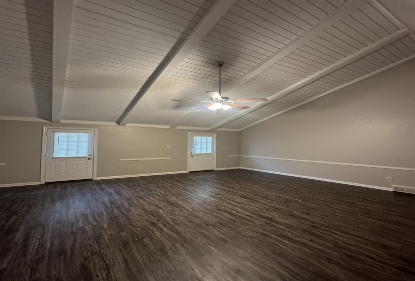 Vaulted plank ceiling with exposed beams and a ceiling fan
