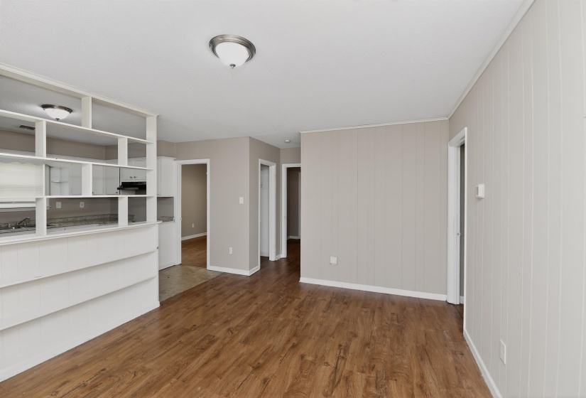 Expansive living area with wood-finish flooring, light-toned vertical paneling, and a semi-flush ceiling light