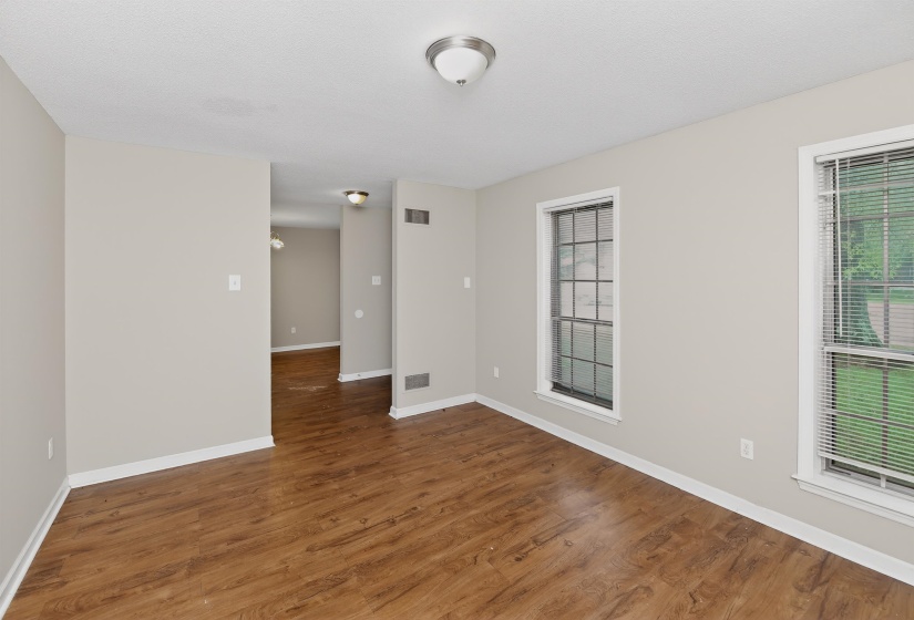 Open concept living area featuring wood-finish flooring, neutral wall tones, and multiple windows for abundant illumination