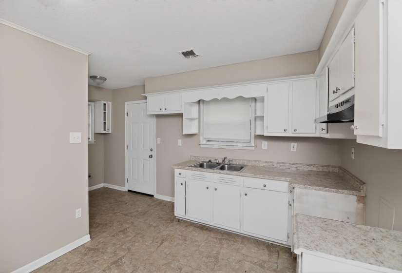 Kitchen with white cabinetry, a double basin stainless steel sink, and light-toned countertops