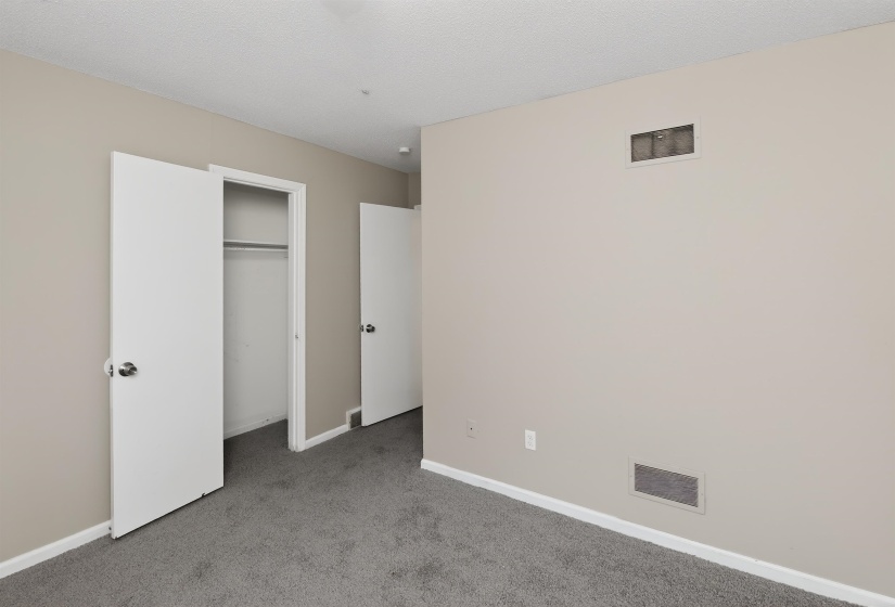 Interior room featuring neutral wall color, gray carpeting, white trim, and white doors with chrome hardware