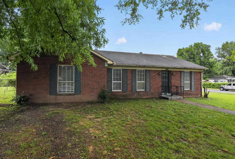 Brick exterior featuring multiple windows with shutters, a front entry with metal railing, and a sloped roofline