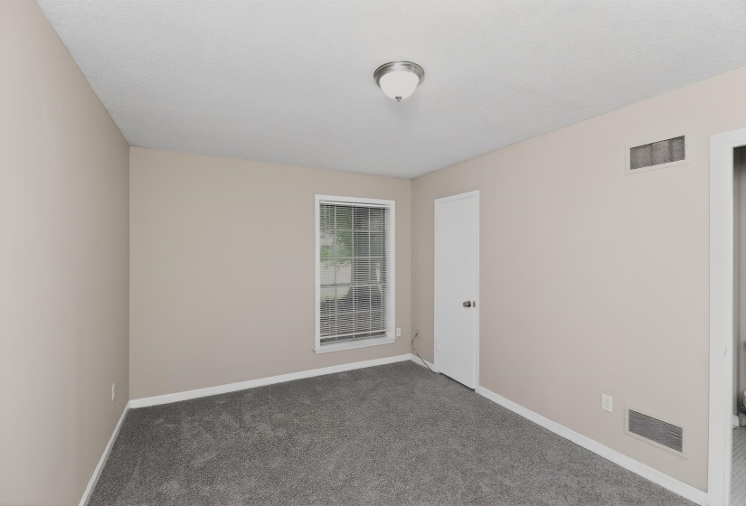 Carpeted room featuring neutral wall tones, a single window with grid panes, white trim, and a flush mount ceiling light fixture