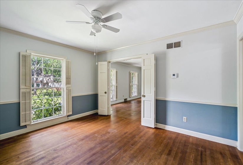 Hardwood-finish flooring throughout, featuring a ceiling fan, crown molding, and a two-tone wall treatment