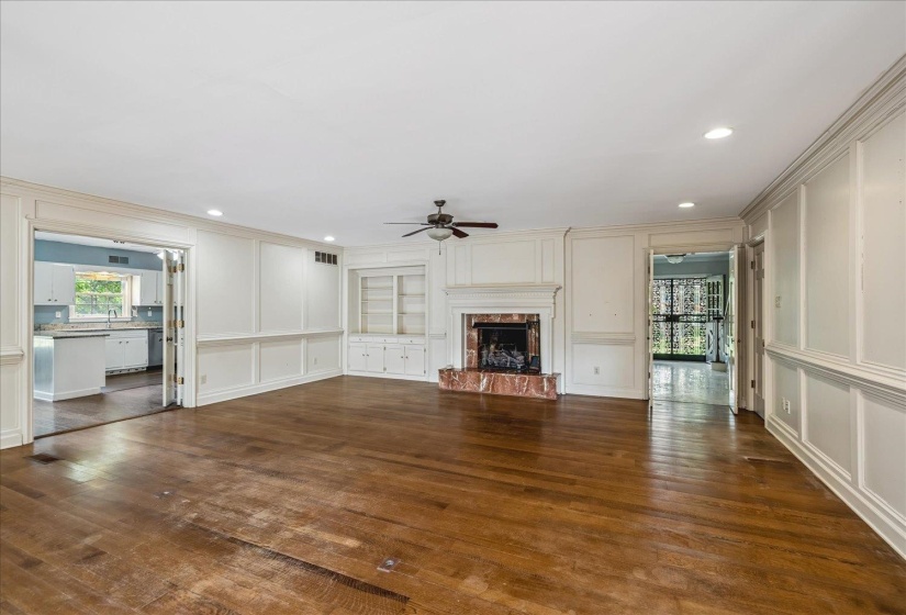 Spacious room featuring wood-finish flooring, a fireplace with a red-toned surround, built-in shelving, and recessed lighting
