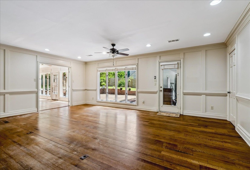 Spacious room with rich wood flooring and extensive wainscoting