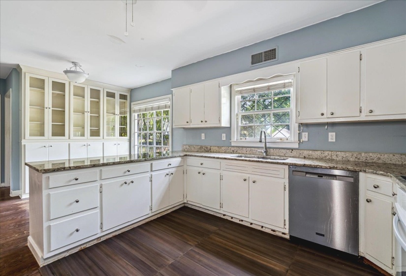 Kitchen featuring white cabinetry, wood-finish flooring, granite countertops, and built-in glass-front display cabinets