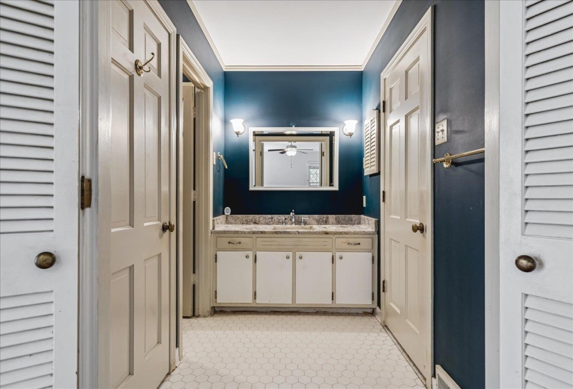 Bathroom vanity featuring a light-colored countertop, dual wall sconces, a framed mirror, and white cabinetry
